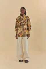 Camisa con estampado de conchas marinas en tonos mostaza y marrón, de corte holgado, mangas largas y cuello clásico.