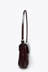 Bolso de hombro color crema con efecto acharolado, solapa con cierre magnético y asa ajustable.
