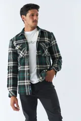 Sobrecamisa de algodón para hombre con interior de corderito, estampado a cuadros en tonos negro, blanco y azul. Tiene cierre de botones, bolsillos tipo cartera y logo en goma. El modelo usa talle M.
