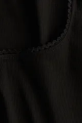 Top negro de punto acanalado de algodón, entallado y de manga larga, con escote pronunciado ribeteado en picot.