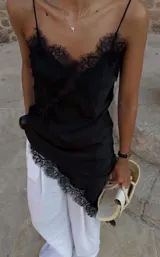 Vestido corto negro con breteles finos, escote en V y terminaciones de encaje.