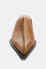 Zueco de piel color camel, con puntera cuadrada y pespunte decorativo en el empeine. Posee un taco alto y grueso de color negro.