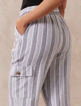Pantalón cargo de lino color blanco, marca Marissa Olivia. Tiene pretina ancha elastizada con lazo de ajuste, bolsillos inclinados delanteros y bolsillos laterales con botón.