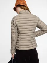 Chaqueta acolchada de nylon en color gris, con cuello alto, cremallera bidireccional y bolsillos laterales con cremalleras invisibles.