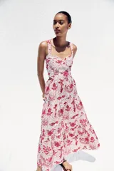 Vestido midi con estampado floral en tonos rosados, de escote recto y tirantes anchos con abalorios. Presenta aberturas laterales en la cintura y cierre trasero con cremallera oculta.