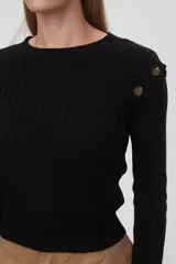 Sweater marrón de punto acanalado con cuello redondo y mangas largas. Presenta botones decorativos en los hombros.