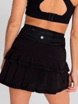 Falda deportiva negra con calza interior, de secado rápido. Diseño acampanado con plisado en la parte trasera, pretina ancha con bolsillo con cierre y bolsillo interior en la calza.