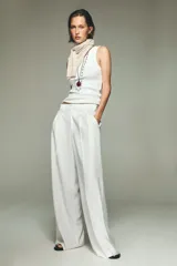 Pantalón blanco de tiro alto con pinzas delanteras, bolsillos laterales y cintura elástica en la parte trasera.