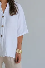 Camisa blanca de lino con cuello mao, manga corta y cierre frontal con botones.