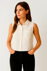 Blusa de algodón color crudo con estampado a cuadros, cuello camisero, cierre frontal con botones, bolsillo en el pecho y corte holgado.