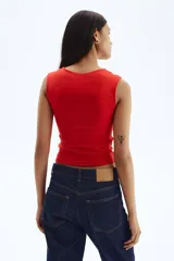 Top corto sin mangas color rojo, de punto suave y ajuste ceñido. Presenta escote corazón profundo y costura fruncida en el centro del busto.