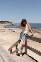 Pareo rectangular de viscosa con estampado de flores rojas sobre fondo borgoña y borde inferior con rayas verticales rojas, amarillas y blancas.