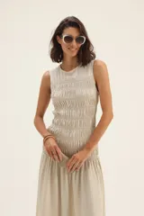 Vestido midi negro de lino, sin mangas, con escote redondo y falda fruncida. Incluye cinturón de cuero trenzado con hebilla metálica.