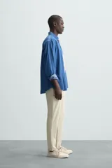 Pantalón largo de vestir gris claro con estampado de cuadros, corte slim fit y cintura elástica. Confeccionado en tejido con alta elasticidad, bolsillos frontales y cierre frontal con cremallera y botón.