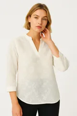 Blusa blanca con bordado floral, escote en V y mangas 3/4.