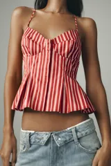 Top con estampado a rayas verticales rojas y blancas, escote pico, tirantes finos ajustables, detalle de pliegues y cierre frontal con botones.