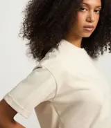 Remera de manga corta color crema, con cuello redondo y corte oversized.