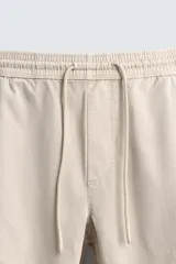 Pantalón jogger negro de corte slim fit, confeccionado en tejido de algodón con cintura elástica ajustable con cordón, bolsillos frontales y traseros de vivo, y bajo con puño elástico.