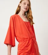 Kimono color naranja de tejido orly con mangas 3/4 con detalle de pompones en el dobladillo, lazo en la cintura y cierre frontal.