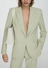 Blazer color verde claro, con cuello de pico con solapa y solapas con muesca. Tiene forro interior, manga larga con puños abotonados, dos bolsillos de solapa en la parte delantera y cierre delantero con botones.