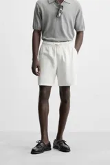 Bermuda negra regular fit confeccionada en tejido de algodón con estructura. Cintura elástica ajustable con cordón, bolsillos laterales y bolsillo trasero de vivo.