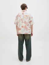 Camisa de manga corta con cuello resort y fit amplio, confeccionada en tejido plano de lino y algodón. Presenta un estampado de mosaicos en tonos rojo, naranja, azul y blanco.