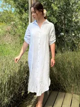 Vestido camisero largo de lino blanco, con corte en la cintura, abertura lateral y botones de nácar.