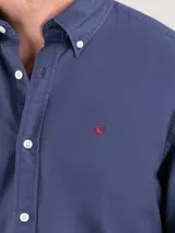 Camisa celeste de algodón con cuello abotonado, manga larga con puños abotonados y logo bordado en el pecho. Corte regular fit y teñido garment dyed para un acabado vintage.