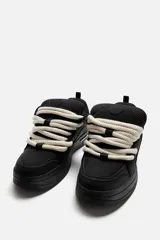 Zapatillas negras de skate con cordones gruesos tipo cuerda, lengüeta acolchada y suela con volumen.
