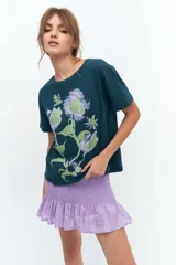 Remera lila de algodón con estampado de flores en tonos naranja y rosa.
