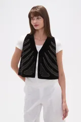 Chaleco negro de terciopelo con escote en V y bordados en hilo plateado que simulan formas orgánicas o de huesos.