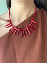 Collar corto de cuentas cilíndricas rojas y bastones de coral rojo.