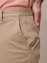 Bermuda color beige, de corte recto y largo hasta la rodilla.