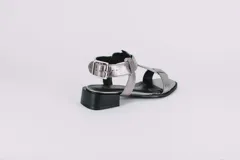 Sandalias de cuero doradas con tiras finas, suela plana y hebilla lateral.