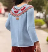 Sweater tejido blanco de hilo 100% algodón, con cuello redondo y diseño con motivos geométricos en el canesú en tonos rojo, verde, azul y negro.