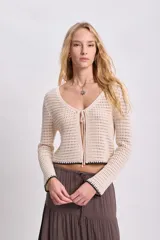 Cardigan de punto crochet color crudo con ajuste frontal con lazos.