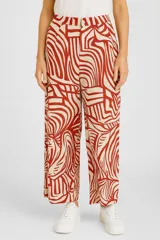 Pantalón de corte holgado con estampado abstracto en tonos rojo y beige.