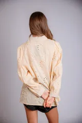 Camisa color beige con bordado inglés, de corte recto, manga larga abullonada con puño y cuello camisero.
