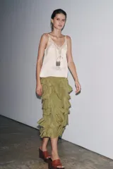 Falda midi color verde oliva confeccionada en tejido con viscosa. Presenta cintura elástica y detalle de volantes en el mismo tejido.