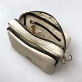 Bandolera color tiza con correa de tela regulable a rayas beige y negro.