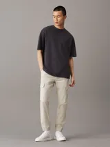 Pantalón cargo color beige de corte skinny, con cintura y puños elásticos, cierre de cremallera y botón de presión, bolsillos delanteros y traseros, bolsillos cargo con solapa, acabado ligeramente lavado e insignia con el monograma de Calvin Klein en la pierna.