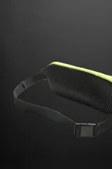 Riñonera deportiva color amarillo flúor, con cierre de cremallera termosellada, bolsillo interno con cremallera y doble mosquetón. Cuenta con banda elástica frontal y asa ajustable con hebilla de liberación rápida.
