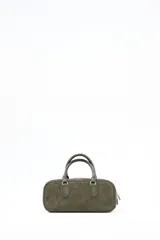 Cartera tipo satchel o bowling bag de cuero gamuzado color verde oliva. Posee dos asas superiores de mano y herrajes metálicos dorados. El nombre de la marca "Lolita" está grabado en dorado en el frente.