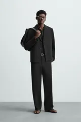 Blazer negro de corte regular, con cuello de solapas de muesca, manga larga con puños abotonados, bolsillos laterales ocultos en la costura de la cadera, bolsillo interior y cierre frontal con botonadura.