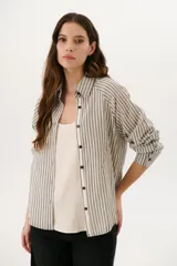 Camisa a rayas verticales color beige y blanco, con cuello clásico, botones marrones y mangas largas.