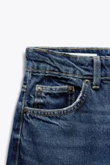 Pantalón de jean negro de tiro alto, corte recto, con cinco bolsillos y cierre frontal con cremallera y botón metálico.