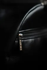 Bolso duffel negro de cuero sintético con logo de ancla bordado en rosa. Tiene doble asa de mano reforzada, correa de hombro regulable y desmontable, cierre superior con doble cremallera y tres bolsillos (dos exteriores y uno interior).