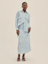 Camisa celeste y blanca con estampado de cebra, de corte holgado, con cuello clásico, cierre frontal con botones, mangas largas con puños abotonados y dos bolsillos de parche en el pecho.
