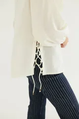 Camisa blanca de popelina de algodón con mangas largas abullonadas y cordones cruzados en los laterales.