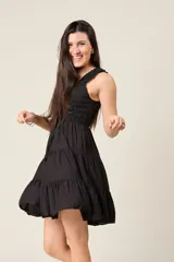 Vestido corto rojo con escote fruncido, tirantes anchos con volantes y cuerpo de nido de abeja. Falda con diseño escalonado.